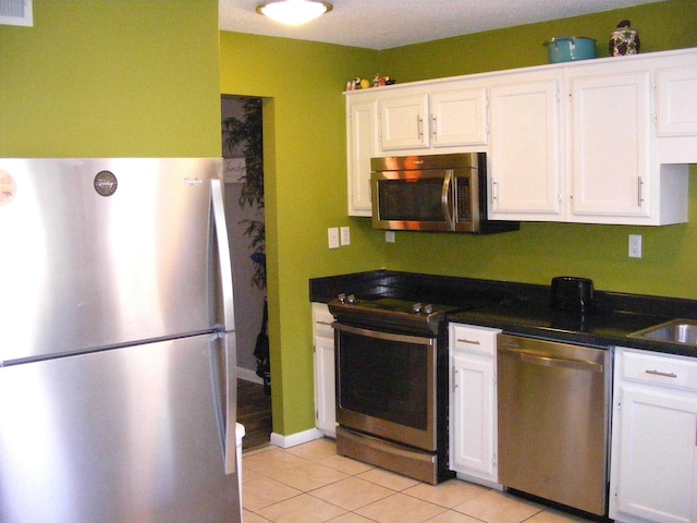 kitchen with light tile patterned flooring, white cabinetry, and appliances with stainless steel finishes