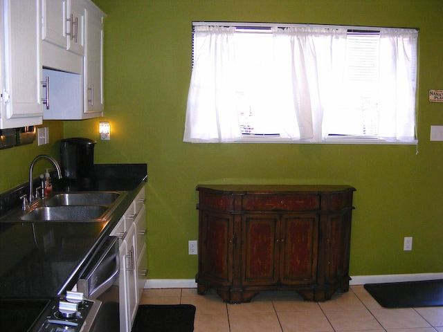 kitchen featuring dishwashing machine, sink, white cabinets, and light tile patterned flooring