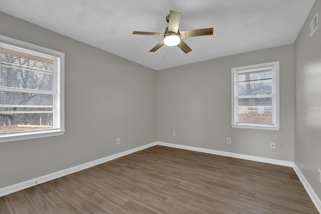 unfurnished room with hardwood / wood-style floors, ceiling fan, and a healthy amount of sunlight