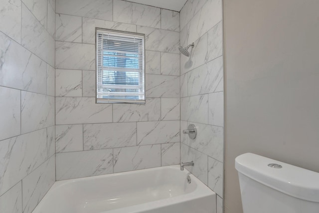 bathroom featuring tiled shower / bath combo and toilet