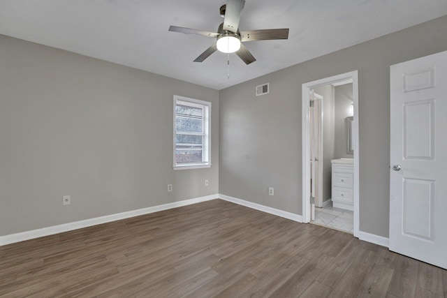 unfurnished bedroom with ceiling fan, light wood-type flooring, and connected bathroom