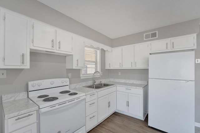 kitchen with white cabinets, white appliances, sink, and hardwood / wood-style flooring