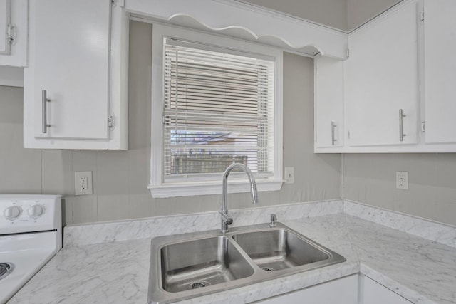 kitchen featuring sink, white cabinets, and stove