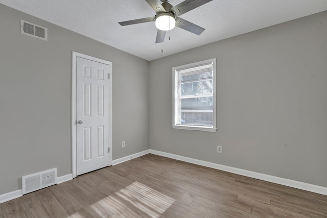 unfurnished room featuring ceiling fan, light hardwood / wood-style flooring, and a textured ceiling