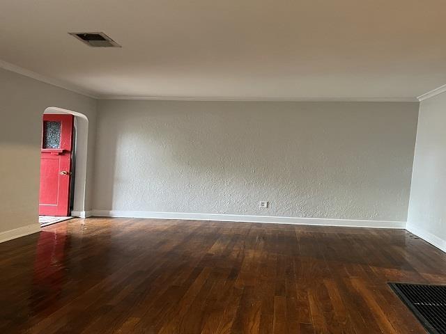 empty room with dark wood-type flooring and crown molding