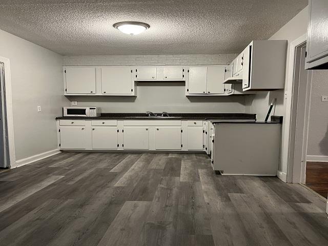 kitchen with white cabinets, a textured ceiling, and dark wood-type flooring