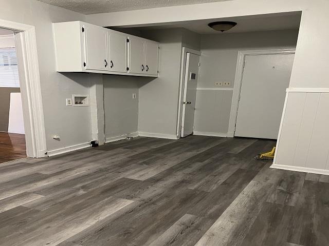 laundry room featuring cabinets, dark hardwood / wood-style flooring, and a textured ceiling