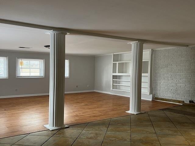 basement with built in shelves, dark tile patterned flooring, and ornamental molding