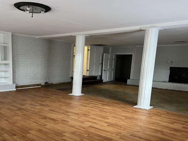 interior space featuring a fireplace, brick wall, built in features, and wood-type flooring