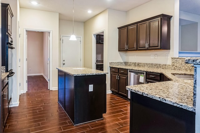 kitchen featuring pendant lighting, a center island, light stone counters, and dark brown cabinetry