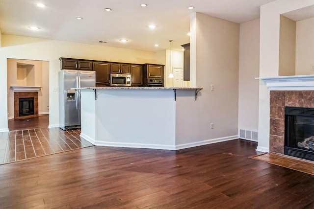 kitchen featuring a breakfast bar, stainless steel appliances, and a tile fireplace