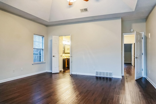 unfurnished bedroom with ceiling fan, dark hardwood / wood-style flooring, a towering ceiling, and connected bathroom