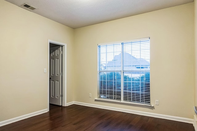 unfurnished room with dark wood-type flooring and a textured ceiling