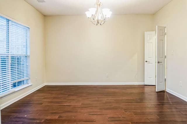 spare room with a chandelier and dark hardwood / wood-style flooring