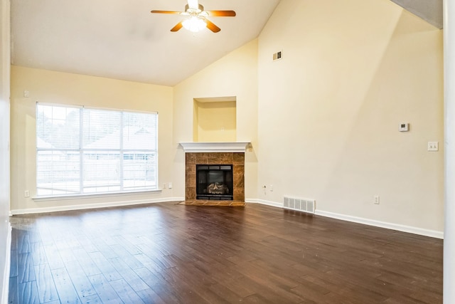 unfurnished living room featuring ceiling fan, dark hardwood / wood-style flooring, high vaulted ceiling, and a tiled fireplace