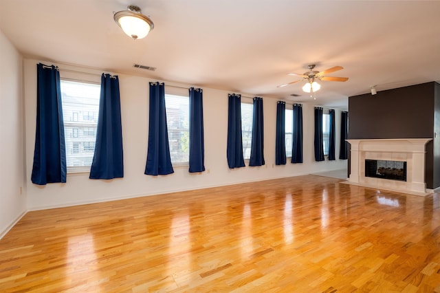 unfurnished living room with ceiling fan, a fireplace, and light hardwood / wood-style flooring