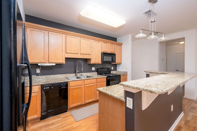 kitchen with pendant lighting, black appliances, sink, light wood-type flooring, and light stone counters