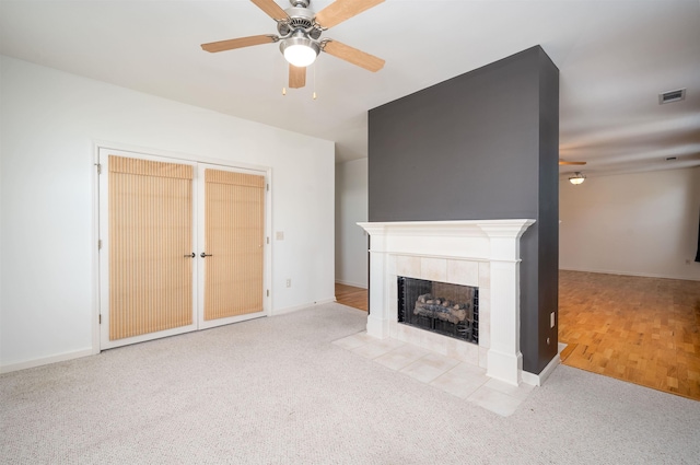 unfurnished living room featuring ceiling fan, light colored carpet, and a tiled fireplace