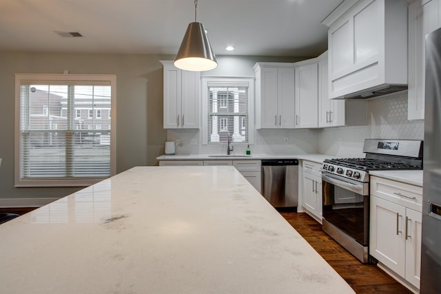 kitchen with white cabinets, appliances with stainless steel finishes, decorative light fixtures, and sink