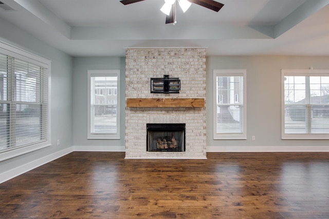 unfurnished living room with a raised ceiling, ceiling fan, and a healthy amount of sunlight