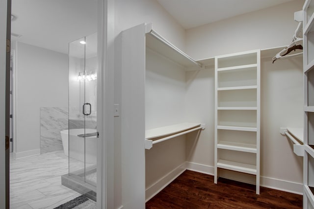 walk in closet featuring a notable chandelier and dark wood-type flooring