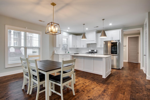 kitchen with decorative backsplash, appliances with stainless steel finishes, dark hardwood / wood-style flooring, decorative light fixtures, and white cabinets