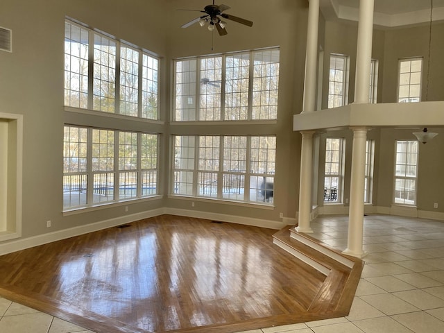 unfurnished sunroom featuring ceiling fan and ornate columns