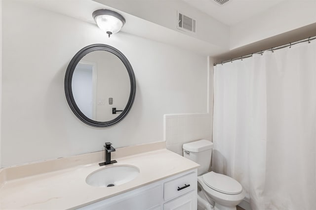 bathroom with vanity, toilet, and tile walls