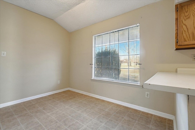 empty room featuring a textured ceiling and vaulted ceiling