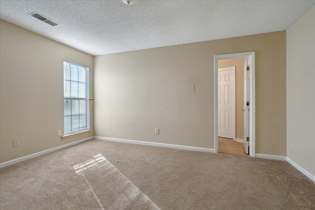 spare room featuring light colored carpet and a textured ceiling