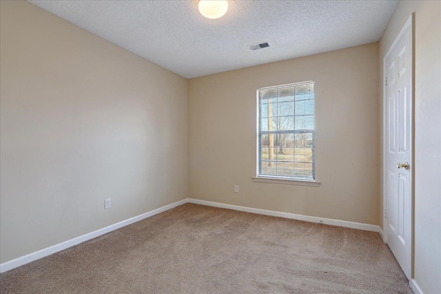 empty room featuring a textured ceiling and light colored carpet