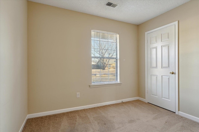 empty room featuring light colored carpet and a textured ceiling