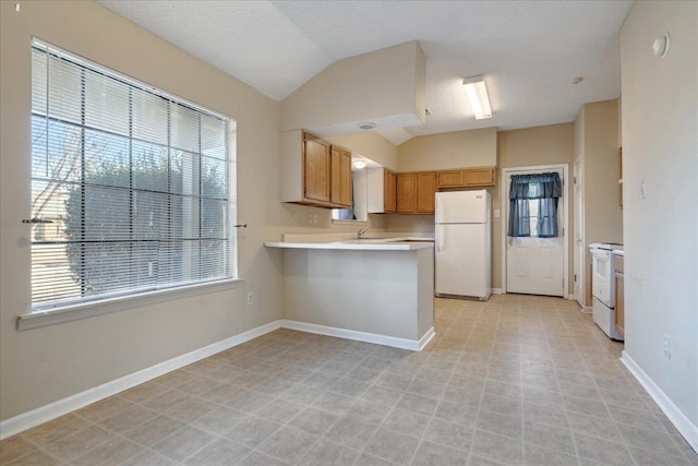 kitchen featuring kitchen peninsula, a textured ceiling, white appliances, and vaulted ceiling