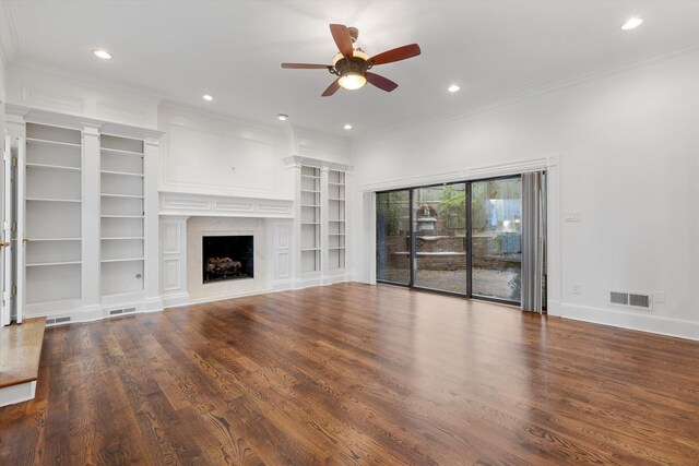 unfurnished living room with ceiling fan, dark hardwood / wood-style floors, built in features, a fireplace, and ornamental molding