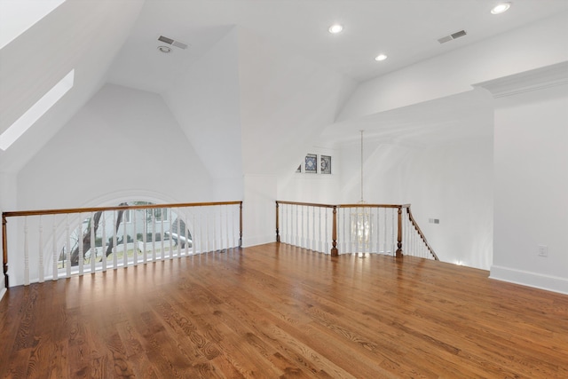 bonus room with vaulted ceiling with skylight, wood-type flooring, and a notable chandelier