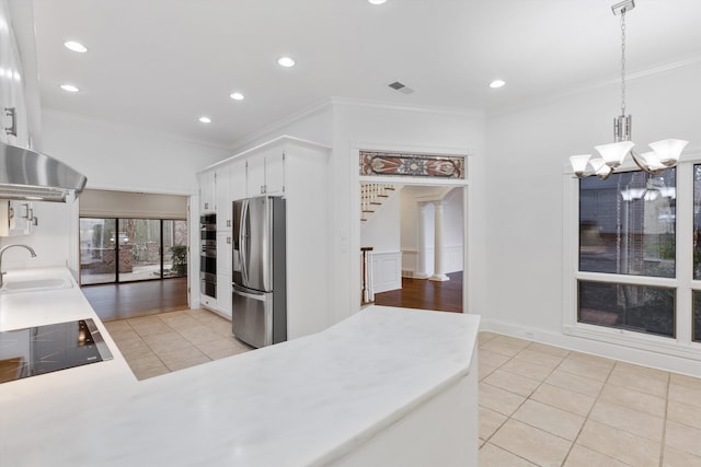 kitchen with stainless steel appliances, sink, light tile patterned floors, decorative light fixtures, and white cabinets