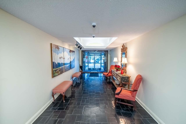 hall with a tray ceiling and a textured ceiling