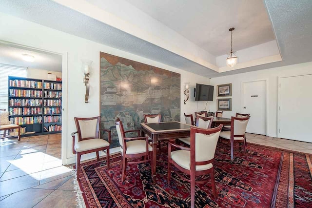 tiled dining room featuring a textured ceiling and a tray ceiling