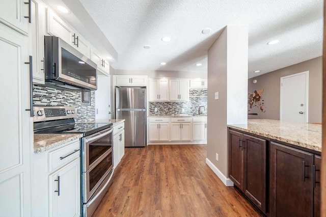 kitchen featuring white cabinets, dark hardwood / wood-style flooring, stainless steel appliances, and light stone countertops