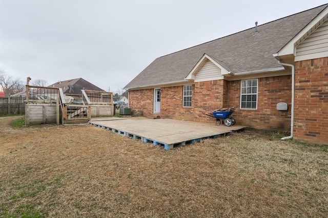 exterior space with a wooden deck, central AC unit, and a lawn