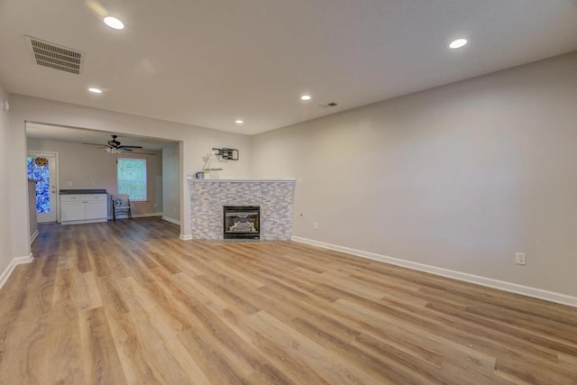 unfurnished living room with a tile fireplace, ceiling fan, and light hardwood / wood-style flooring