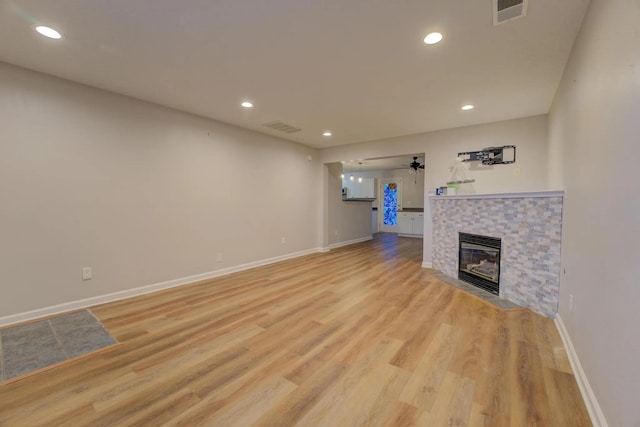 unfurnished living room with light hardwood / wood-style floors, ceiling fan, and a tiled fireplace