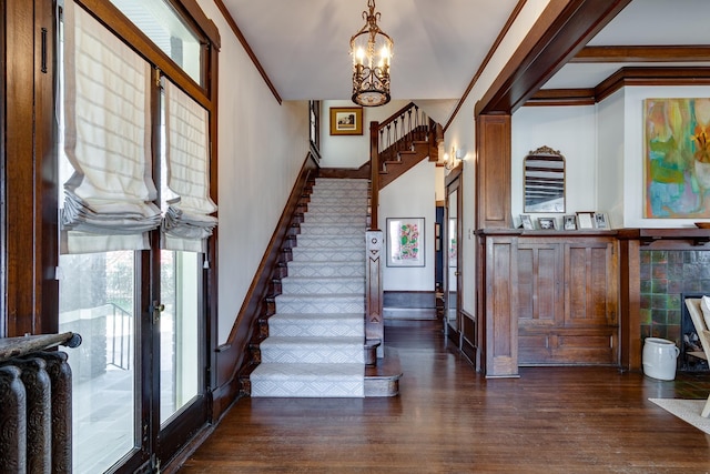 entryway with a notable chandelier, dark hardwood / wood-style flooring, and crown molding