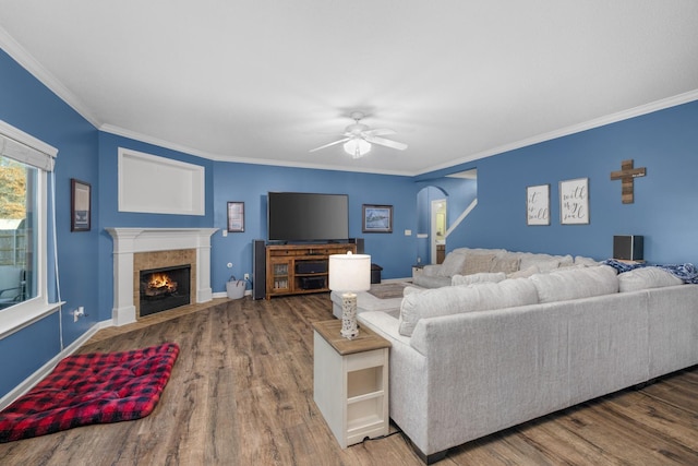 living room with crown molding, ceiling fan, hardwood / wood-style floors, and a tile fireplace