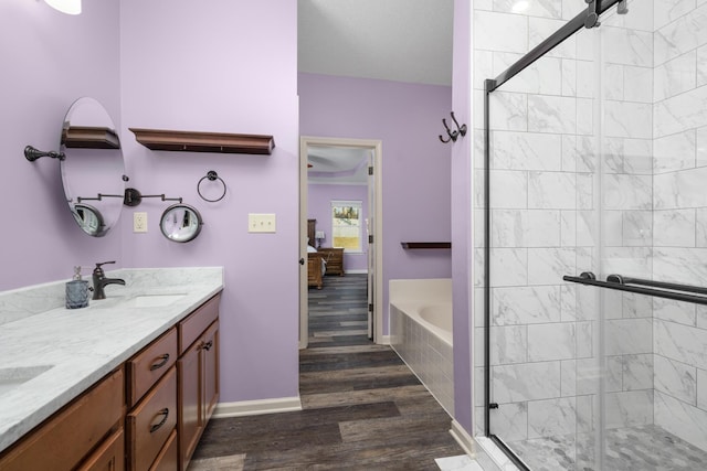 bathroom with hardwood / wood-style flooring, plus walk in shower, and vanity