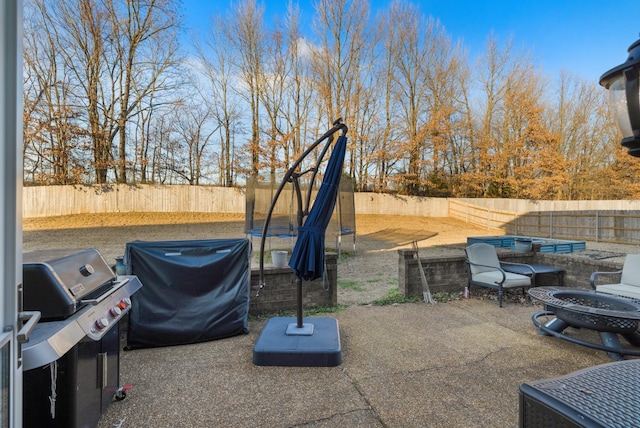 view of patio featuring a trampoline, a grill, and a fire pit