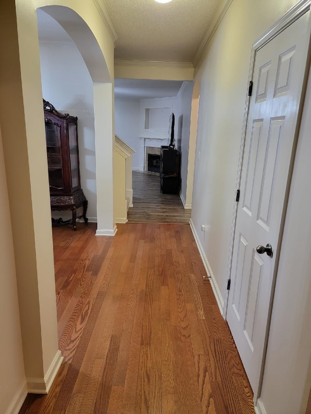 hallway with crown molding, wood-type flooring, and a textured ceiling