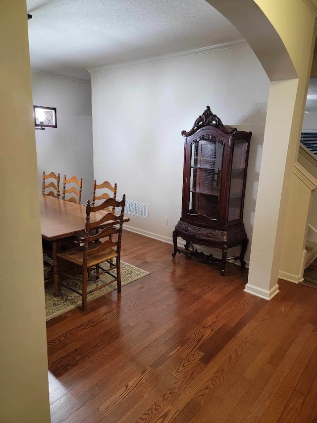 dining room with crown molding, a textured ceiling, and dark hardwood / wood-style flooring