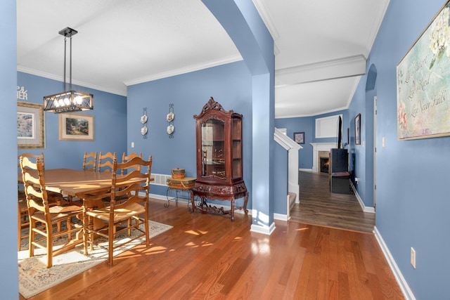 dining space featuring wood-type flooring and crown molding