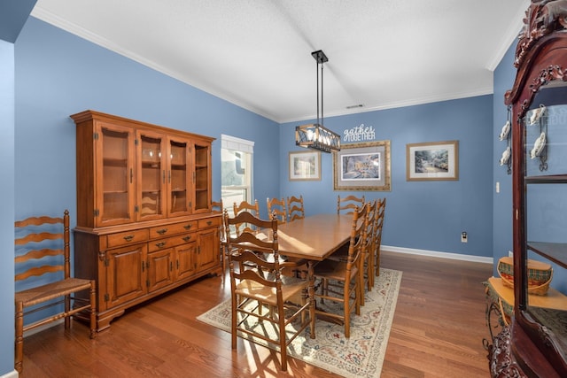 dining area featuring crown molding, dark hardwood / wood-style floors, and a chandelier